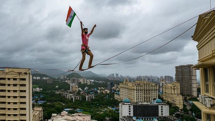Pria India Ini Kibarkan Bendera dengan Meniti Seutas Tali di Ketinggian MUMBAI, INDIA AUGUST 15: Harsdeep Pawar of Team Slackistan walks on the highline rigged at a height of approximately 250 feet with the Indian Tricolour in his hand as part of the