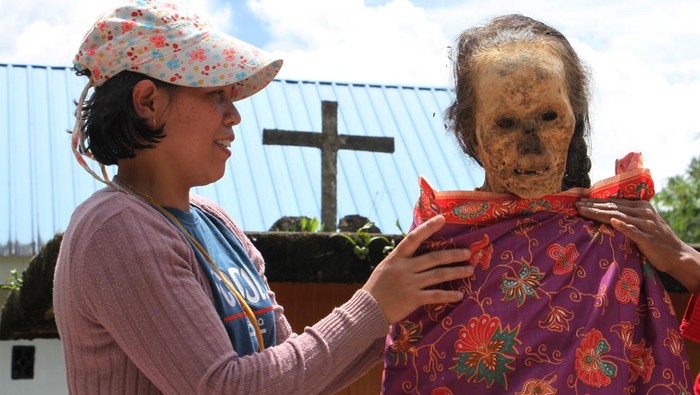 Kerabat memasukkan kembali jenazah keluarganya ke dalam peti saat ritual Manene di Lembang Ampang Batu, Kabupaten Toraja Utara, Sulawesi Selatan, Senin (15/8/2022). Ritual yang digelar secara turun temurun oleh masyarakat Toraja tersebut untuk mengganti dan membersihkan jenazah keluarga sebagai bentuk penghormatan dan kasih sayang terhadap leluhur mereka. ANTARA FOTO/Arnas Padda/wsj.