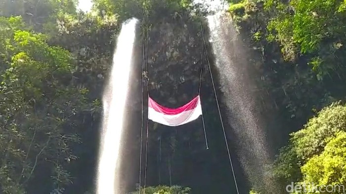 Bendera raksasa berkibar di air terjun Tasikmalaya.