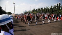 Orang-orang yang mengiringi mengenakan pelbagai busana adat dari seluruh Indonesia. Pasukan drum band TNI, juga kepolisian mengiringi dengan gagah. Masyarakat berkerumun dan melihat dengan antusias. 