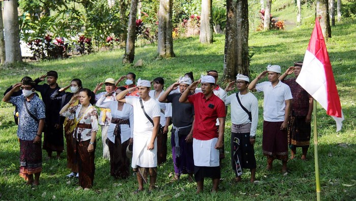Warga dan mahasiswa mengenakan busana adat Bali saat mengikuti pengibaran bendera merah putih di kawasan Hutan Desa Manistutu, Jembrana, Bali, Selasa (16/8/2022). Kegiatan yang digelar oleh mahasiswa Universitas Hindu Negeri I Gusti Bagus Sugriwa yang melaksanakan kuliah kerja nyata (KKN) di desa tersebut untuk memeriahkan HUT Kemerdekaan ke-77 Republik Indonesia serta mengajak masyarakat untuk menjaga dan melestarikan hutan. ANTARA FOTO/Nyoman Hendra Wibowo/hp.