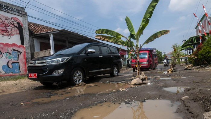 Pengendara roda dua melintas dijalan yang rusak di Kolelet, Lebak Banten, Rabu (17/8/2022). Penanaman pohon pisang di jalan penghubung Kabupaten Serang dan Kabupaten Lebak tersebut dilakukan warga setempat sebagai bentuk protes karena jalan rusak yang tidak kunjung diperbaiki oleh pemerintah daerah. ANTARA FOTO/Muhammad Bagus Khoirunas/rwa.