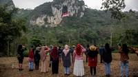 Warga memberikan hormat kepada bendera yang berkibar di atas bukit. (Raisan Al Farisi/Antara Foto)