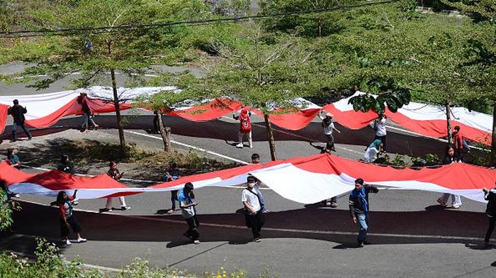 TANA TORAJA, INDONESIA - AUGUST 17: Environment activists raise the Indonesian flag with a length of 77 meters around the tallest Jesus statue in the world with a height of 1,700 meters above sea level in Tana Toraja, South Sulawesi, Indonesia, Wednesday 17 August 2022. The 77-meter flag raising ceremony was held to commemorate the 77th Independence Day of Indonesia. (Photo by Zul Kifli/Anadolu Agency via Getty Images)