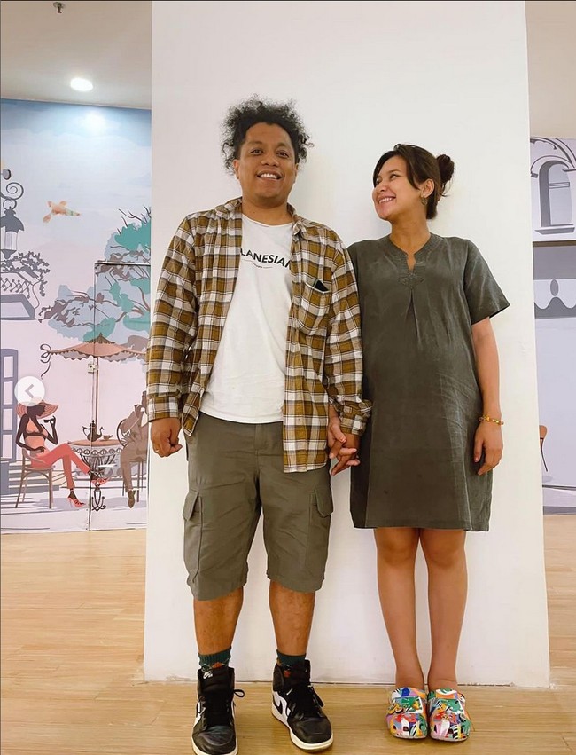 Indah Permatasari tampil casual dengan mini dress berpotongan longgar dan Arie Kriting mengenakan kaus yang dipadu kemeja tartan dan celana bermuda. Foto: Instagram/@arie_kriting