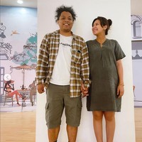 Indah Permatasari tampil casual dengan mini dress berpotongan longgar dan Arie Kriting mengenakan kaus yang dipadu kemeja tartan dan celana bermuda. Foto: Instagram/@arie_kriting