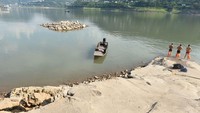 Tiga perenang bersiap untuk masuk ke air setelah permukaan air turun di Sungai Yangtze di daerah Yunyang di barat daya Kota Chongqing. China mengambil tindakan darurat untuk mengatasi kekeringan di lembah sungai Yangtze. Sejumlah cara dilakukan seperti mengirimkan lebih banyak air, menggelontorkan lebih banyak bantuan, penyemai awan dan membangun sumber air baru. Langkah ini diambil saat gelombang panas merusak lahan pertanian dan peternakan. (Rao Guojun/Future Publishing/Getty Images)