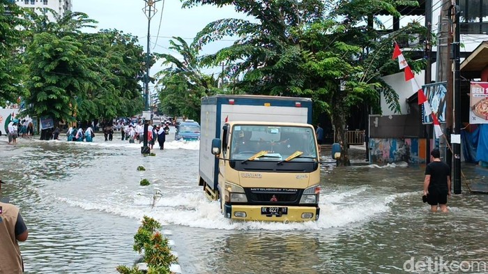Kendaraan berusaha menerobos banjir di Jalan Dr Mansyur Medan.