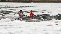 Atlet kayak harus berlatih di tengah busa limbah sungai. 