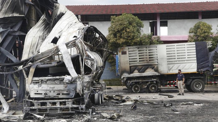 A Thai officer stands beside the burnt down oil tanker at a gas station in Pattani province, southern Thailand, Wednesday, Aug. 17, 2022. A wave of arson and bombing attacks overnight hit Thailand’s southernmost provinces, which for almost two decades have been the scene of an active Muslim separatist insurgency, officials said Wednesday. (AP Photo/Sumeth Panpetch)