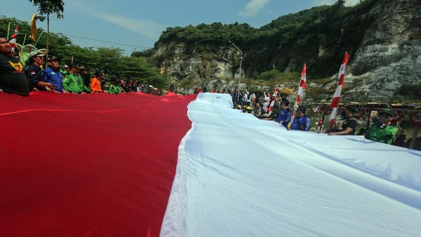 Sejumlah warga membawa bendera merah putih untuk dikibarkan di Gunung Kapur, Kawasan Wisata Goa Lalay, Klapanunggal, Kabupaten Bogor, Jawa Barat, Rabu (17/8/2022). Pengibaran bendera merah putih berukuran 30X6 meter di atas gunung kapur tersebut untuk menyambut perayaan HUT ke-77 Republik Indonesia. (Yulius Wijaya/AntaraFoto)