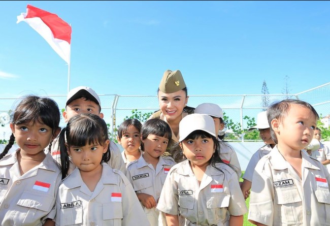 Upacara bendera itu berlangsung di rooftop gedung sekolahnya. Terlihat latar belakang pemandangan yang asri dan bendera merah putih yang berkibar. Foto: Instagram/@yunishara36