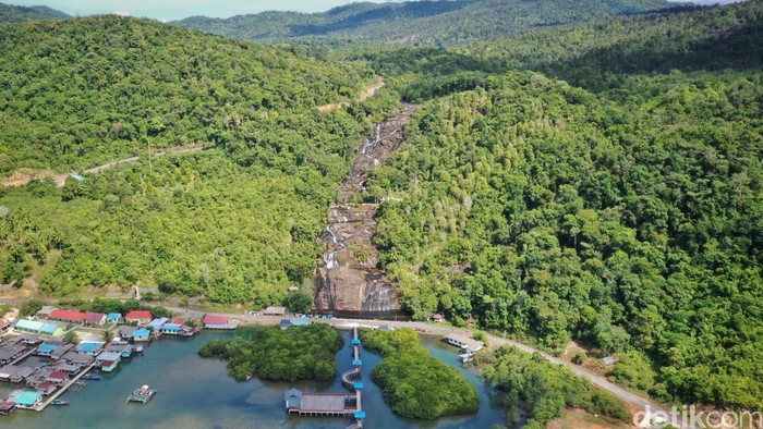 Pengendara motor melintas di depan Air Terjun Temburun di Pulau Siantan, Kabupaten Kepulauan Anambas, Kepulauan Riau, Selasa (2/8/2022). Kepulauan Anambas menyimpan beragam destinasi wisata yang menarik untuk dikunjungi. Tidak heran bila kabupaten termuda di Provinsi Kepulauan Riau ini kerap dijuluki surga kecil di perbatasan Indonesia.