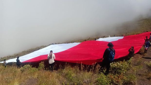 Peserta upacara pengibaran bendera raksasa di lereng Gunung Tambora