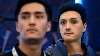 Sebuah robot yang dirancang dengan fitur wajah yang sama dengan seorang pria (depan) terlihat pada Konferensi Robot Dunia 2022.