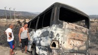 Pria memeriksa bus yang terbakar setelah kebakaran hutan di El Kala, Provinsi Al Taref, Aljazair.