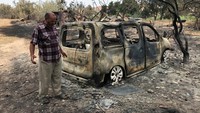 Petani Aljazair Ziani Omar berdiri di dekat kendaraan yang terbakar akibat kebakaran hutan di El Kala, Provinsi Al Taref, Aljazair 18 Agustus 2022.