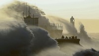 Sejumlah orang terlihat menyaksikan ombak tinggi yang menghantam tembok di Porthcawl, Wales, pada 18 Februari 2022. Lagi-lagi, gelombang pasang ini tercipta imbas Badai Eunice.
