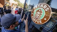 Seorang warga memotret logo Stars Coffee.