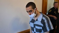 Hadi Matar mengenakan pakaian jumpsuit hitam-putih, masker putih, dan tangan yang diborgol.  Foto: AFP via Getty Images/ANGELA WEISS