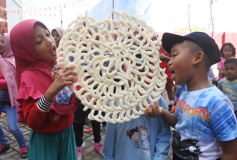 Sejumlah warga mengikuti lomba makan kerupuk di Kelurahan Ardirejo, Panji, Situbondo, Jawa Timur, Minggu (21/8/2022). Berbagai jenis lomba digelar Kelurahan Ardirejo yang diikuti seluruh warga untuk memeriahkan peringatan HUT ke-77 Kemerdekaan RI, termasuk makan kerupuk ukuran jumbo. ANTARA FOTO/Seno/aww.