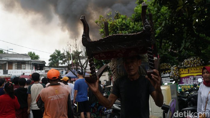 Sejumlah warga dibantu dengan petugas pemadam kebakaran mencoba memadamkan api yang melahap tempat tinggal warga di kawasan Permata Hijau, Simprug, Jakarta Selatan, Minggu (21/8/2022).