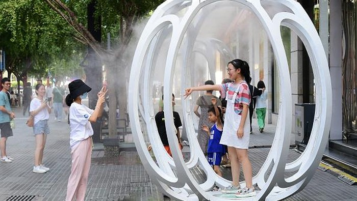 Banyak 'Kulkas' di Jalanan China Saat Panas Menyegat JINHUA, CHINA - AUGUST 20: People play in an installation spraying cooling mist on the street during the heat wave on August 20, 2022 in Jinhua, Zhejiang Province of China. (Photo by Shi Bufa/VCG via Getty Images)