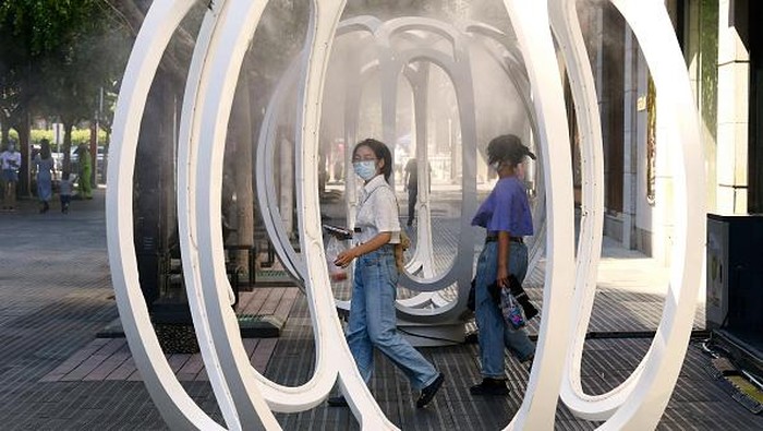JINHUA, CHINA - AUGUST 20: People play in an installation spraying cooling mist on the street during the heat wave on August 20, 2022 in Jinhua, Zhejiang Province of China. (Photo by Shi Bufa/VCG via Getty Images)