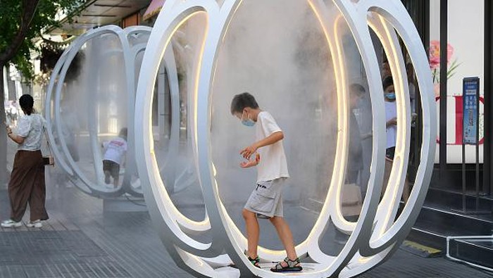 JINHUA, CHINA - AUGUST 20: People play in an installation spraying cooling mist on the street during the heat wave on August 20, 2022 in Jinhua, Zhejiang Province of China. (Photo by Shi Bufa/VCG via Getty Images)