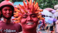 Bak virus korona, pria ini melumuri warahnya berwarna merah serta memakai hiasan di kepalanya seperti bentuk virus korona. Terlihat pria dibelakang, wajahnya juga berwarna merah dan memakai helm sebagai hiasan kepalanya.