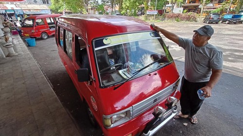 Sopir angkutan umum I Ketut Sukanadi sedang membersihkan mobilnya saat mangkal di Terminal Pesiapan, Senin (22/8/2022).