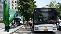 Sebuah bus berhenti di depan halte. Terlihat para penumpang turun dari bus tersebut.