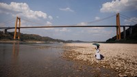 Seorang warga berdiri di atas batu di tengah sungai Yangtze di Chongqing, China, Sabtu (20/8/2022),  