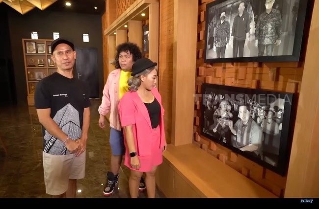 Berkat kerja kerasnya, Ajik Krisna kini memiliki 32 toko oleh-oleh di Bali. Pada rumahnya yang mewah ini, dia tak melupakan jasa-jasa orang yang telah membantunya. Dia memajang foto guru spiritualnya sekaligus mantan bosnya di mana dulu dia bekerja. Foto tersebut dipajang bersama dengan foto-foto lainnya di mana Ajik bertemu presiden hingga selebriti Indonesia. Foto: Dok. YouTube Trans7 Sobat Misqueen