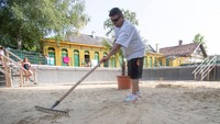 Seorang penjaga pantai menyapu pasir di bekas kolam renang wanita yang kosong dan dipenuhi pasir di pemandian air panas Bad Fischau. Pengelola pemandian air panas Belle Epoque Bad Fischau harus menutup beberapa kolam karena beberapa sumber mata air hangat telah mengering.