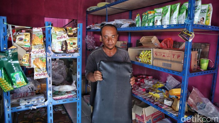 Samsul Kabari (42) keluar dari toko kelontong miliknya di Desa Batu Belah, Kabupaten Kepulauan Anambas, Kepulauan Riau, Senin (1/8/2022). Samsul dan istrinya membangun toko kelontong yang sekaligus agen BRILink.