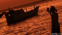 Siluet traveler memotret momen matahari terbenam. Pantai ini yang berada di ibu kota provinsi ini terpantau bersih.