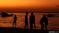 Siluet manusia terekam dengan apik di sini. Terdapat juga perahu yang bersandar di dekat pantai.