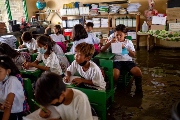 Students attend the first day of in-person classes, at a flooded school due to high tide, in Macabebe, Pampanga province, Philippines, August 22, 2022. REUTERS/Lisa Marie David