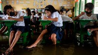 Para siswa belajar dengan serius dan teliti. Mereka menggunakan sendal saat belajar lantaran lantai kelas kebanjiran.
