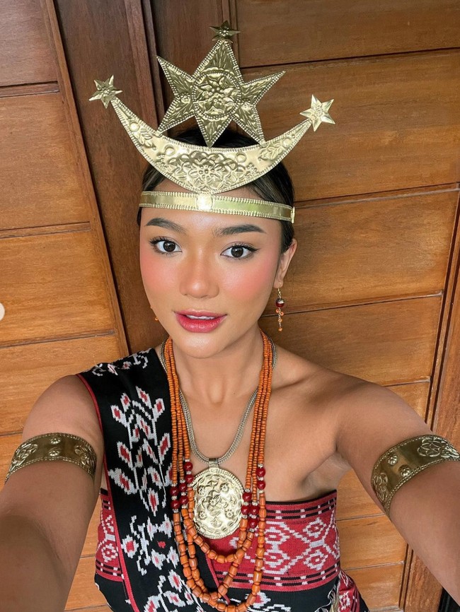 Pakaian adat yang dikenakan oleh Marion itu lengkap dengan beragam aksesorinya, seperti hiasan kepala dan lengan, gelang, anting, serta kalung. Dengan pulasan makeup natural, penampilan Marion Jola pun jadi makin menawan. Foto: Instagram/@lalamarionmj