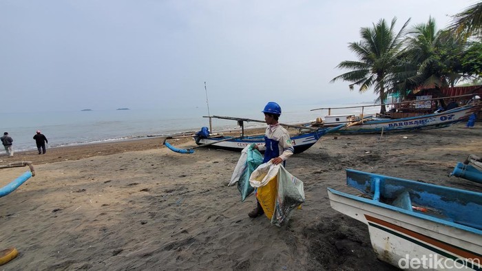 Petugas tengah membersihkan batu bara yang sempat mencemari Teluk Palabuhanratu, Sukabumi