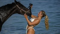 Turis wanita yang senang bermain dengan kuda di Laut Karibia.