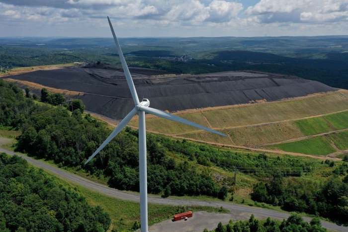 1417457299 OAKLAND, MARYLAND - AUGUST 23: In an aerial view, turbines from the Roth Rock wind farm spin on the spine of Backbone Mountain next to the Mettiki Coal processing plant on August 23, 2022 in Oakland, Maryland. The 50,000 kilowatt Roth Rock project has 20 Nordex N90/2500 turbines and has been operating since 2011. Once Maryland’s largest coal mine, the Mettiki pulled a total of 55 million short tons from the Upper Freeport seam in Garrett County’s southwestern corner between 1983 and 2006, when the mine was closed. Today, the former mine site still washes, separates and processes coal from nearby mines. (Photo by Chip Somodevilla/Getty Images)