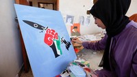 Seorang seniman melukis sebuah roket dengan bendera Palestina dan tulisan Gaza.