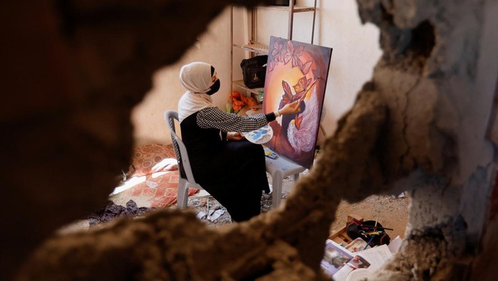 A Palestinian artist draws a painting inside the damaged house of Gaza artist, Duniana Al-Amour, who had been killed during Israel-Gaza fighting earlier this month, in Khan Younis in the southern Gaza Strip August 23, 2022. REUTERS/Ibraheem Abu Mustafa