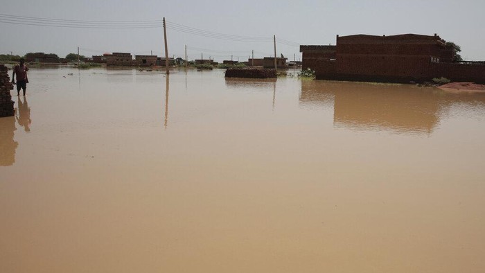 A man walks in floodwaters after heavy rainfall in the village of Aboud in the El-Manaqil district of the Al-Jazirah province, southeast of Khartoum, Sudan, Tuesday, Aug. 23, 2022. The death toll from flash floods in Sudan since the start of the country's rainy season has climbed to over 80, an official said Tuesday as the downpours continued to inundate villages across the east African nation. The United Nations said more than 146,200 people have been affected by floods. (AP Photo/Marwan Ali)