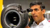 Rishi Sunak memicingkan mata dibalik teropong militer anti tank saat berkunjung ke Thales Defence System, Belfast, Irlandia utara, yang menjadi bagian dari kampanye politiknya menjadi perdana menteri, Rabu (17/8/2022). (Paul Faith/PA via AP)