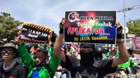 Driver ojek online (ojol) mengangkat poster yang dibawa untuk demo/Foto: Deny Prastyo Utomo/detikJatim