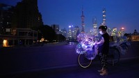 Penjual mainan berdagang di kegelapan, dengan pemandangan kota Shanghai di belakangnya. The Bund, situs ikonik Kota Shanghai, China, terpaksa dimatikan selama dua malam untuk menghemat listrik.  